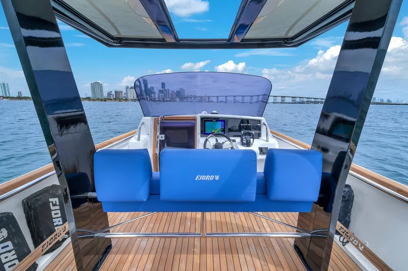 No Name Yacht Photos Pics Fjord 38 boat interior with blue seating, modern dashboard, and scenic waterfront view.