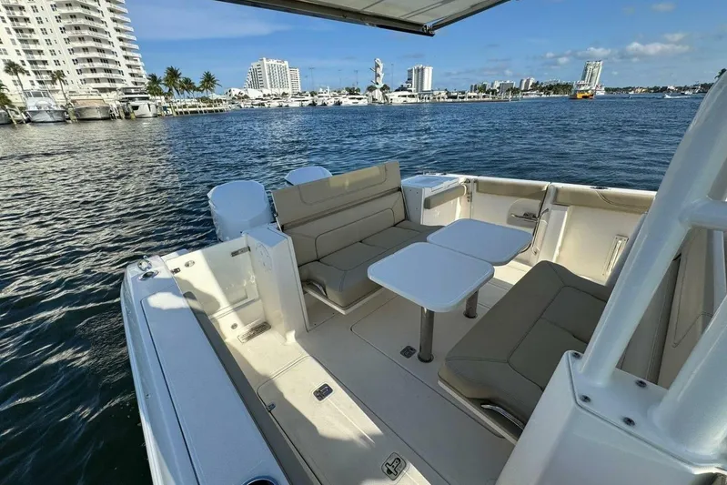  Yacht Photos Pics 2020 Pursuit S 328 Sport boat interior with seating and tables, docked near waterfront buildings.