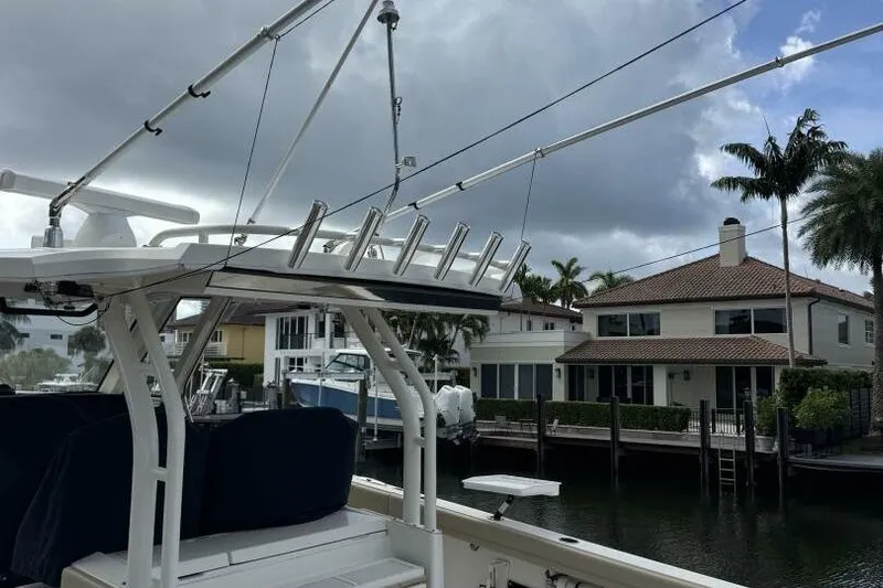  Yacht Photos Pics 2020 Pursuit S 328 Sport boat docked near waterfront homes under cloudy sky.