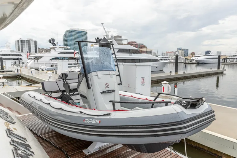 Fat Cat Yacht Photos Pics Docked Zodiac boat on Sunreef 80 Power yacht, 2024 model, in a marina with cityscape background.