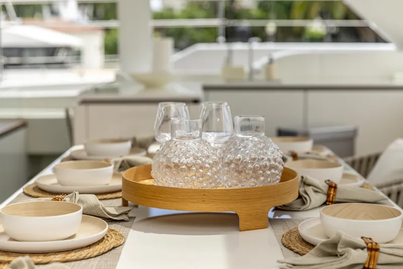 Fat Cat Yacht Photos Pics Elegant dining setup on 2024 Sunreef 80 Power yacht, featuring stylish tableware and glass decanters.