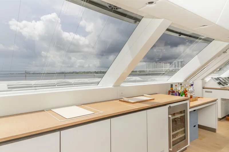 Fat Cat Yacht Photos Pics Luxurious interior of 2024 Sunreef 80 Power yacht with panoramic windows and modern bar setup.