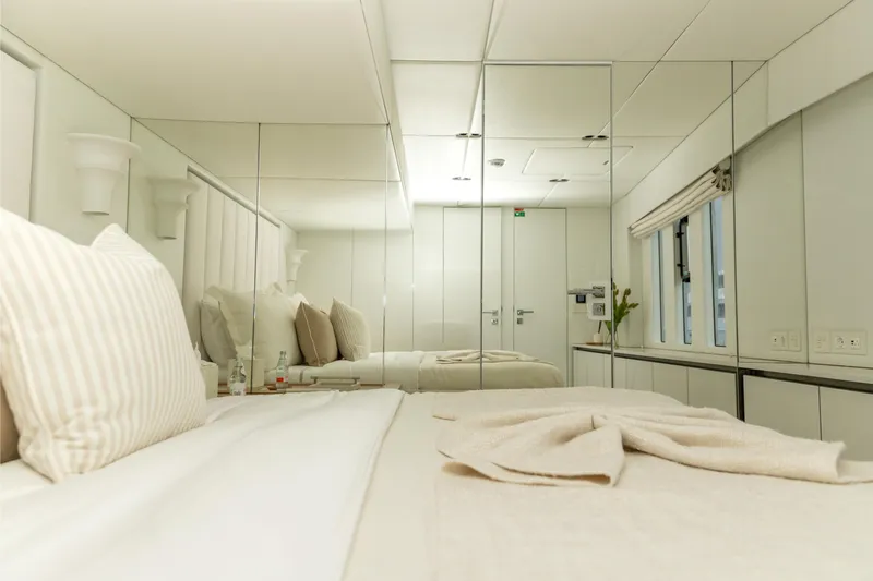 Fat Cat Yacht Photos Pics Luxurious bedroom interior of 2024 Sunreef 80 Power yacht with mirrored walls and elegant decor.