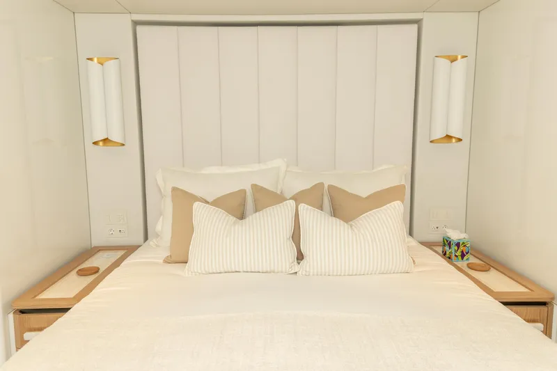 Fat Cat Yacht Photos Pics Luxurious bedroom interior on 2024 Sunreef 80 Power yacht, featuring elegant bedding and modern lighting.