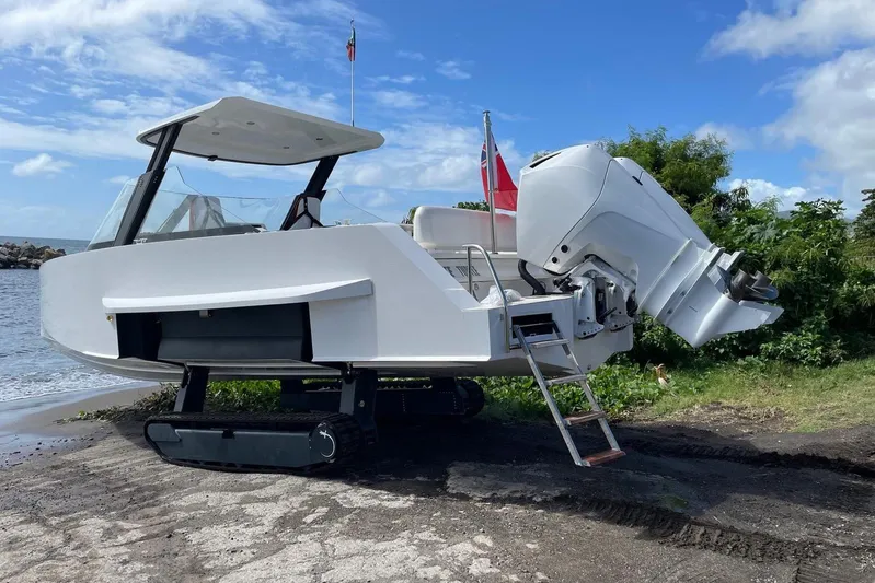  Yacht Photos Pics 2019 IGUANA Yachts Commuter with amphibious tracks on a beach, under a clear blue sky.