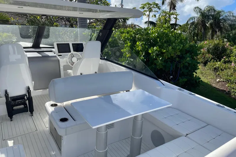  Yacht Photos Pics 2019 IGUANA Yachts Commuter interior with white seating and table, surrounded by lush greenery.