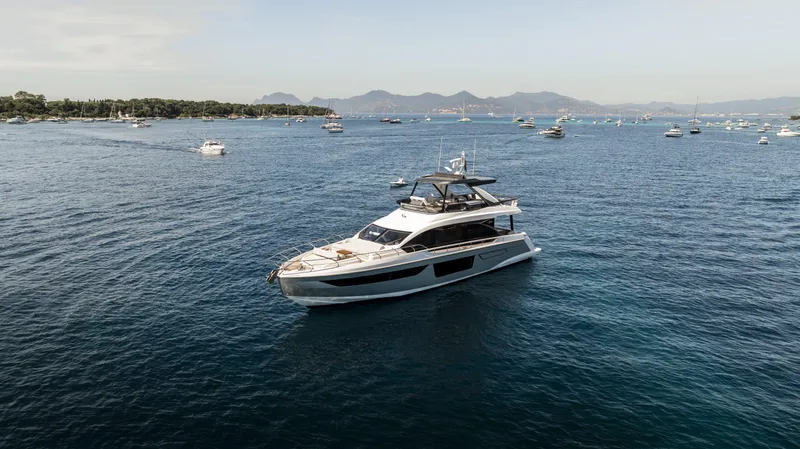  Yacht Photos Pics 2023 Azimut Fly 68 yacht cruising on a serene blue sea with distant mountains.