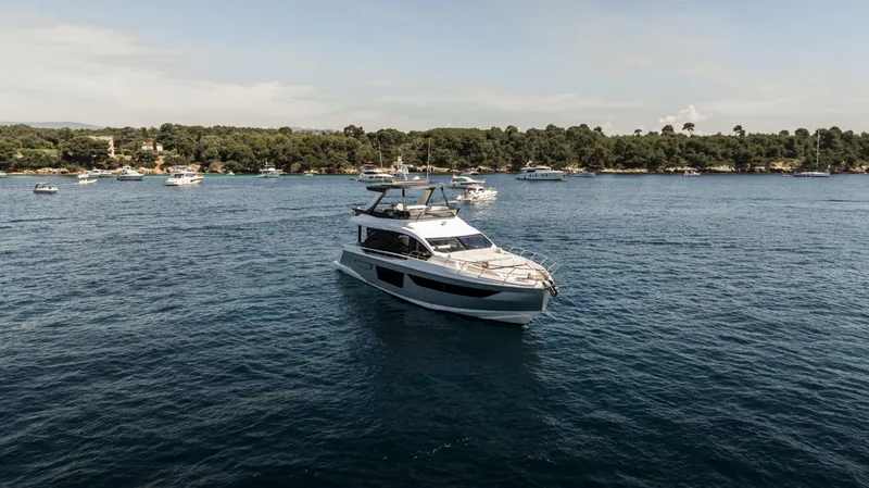  Yacht Photos Pics 2023 Azimut Fly 68 yacht cruising on a serene blue sea with lush green shoreline.