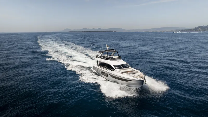  Yacht Photos Pics 2023 Azimut Fly 68 yacht cruising on open sea with scenic coastline.