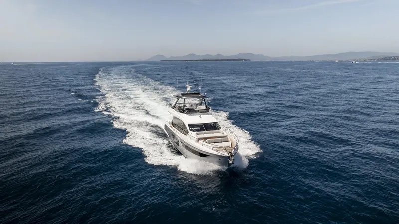  Yacht Photos Pics 2023 Azimut Fly 68 yacht cruising on open sea with scenic coastline.