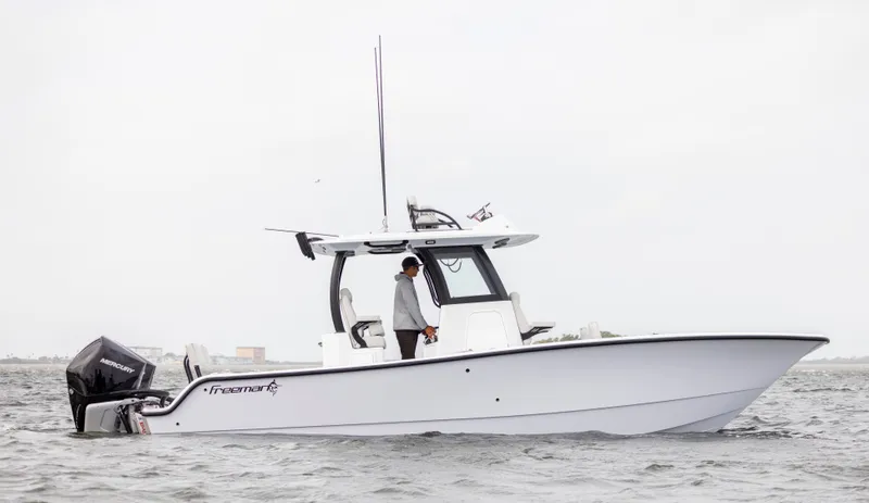  Yacht Photos Pics 2024 Freeman 28 boat on water with person standing at helm.