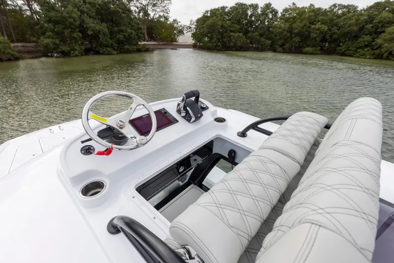  Yacht Photos Pics 2024 Freeman 28 boat cockpit with steering wheel and dual seats on a calm river.