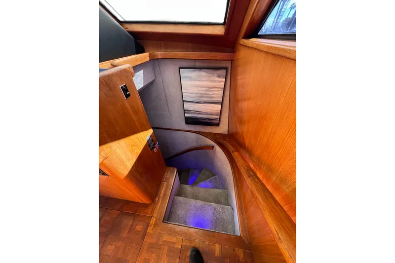 Kailani Yacht Photos Pics Interior staircase to forward guest berths with wooden paneling and artwork.