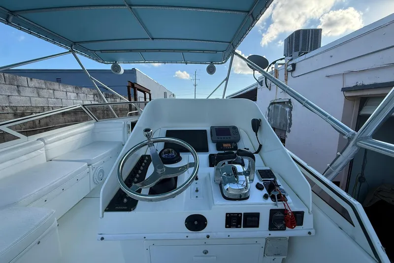 Reel Dreamz Yacht Photos Pics 1998 Contender 35 Express boat helm with steering wheel and controls under blue canopy.