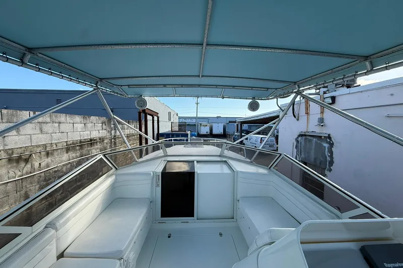 Reel Dreamz Yacht Photos Pics 1998 Contender 35 Express boat interior with seating and canopy, docked near industrial buildings.