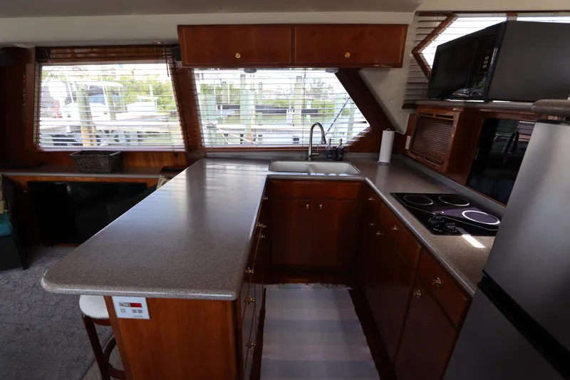 Fitz Perfectly Yacht Photos Pics 2001 Navigator 4800 CLASSIC yacht kitchen with wooden cabinets, countertop, stove, and sink.
