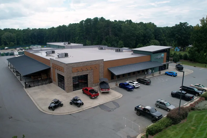  Yacht Photos Pics Aerial view of a commercial building with parked vehicles, surrounded by trees.