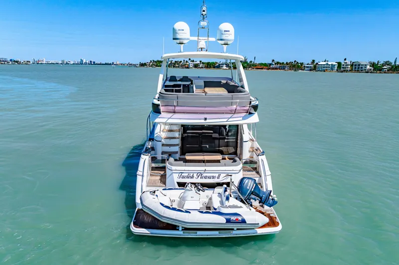 Fuelish Pleasure II Yacht Photos Pics Luxury Princess 56 yacht from 2017 on calm waters, featuring a small boat.