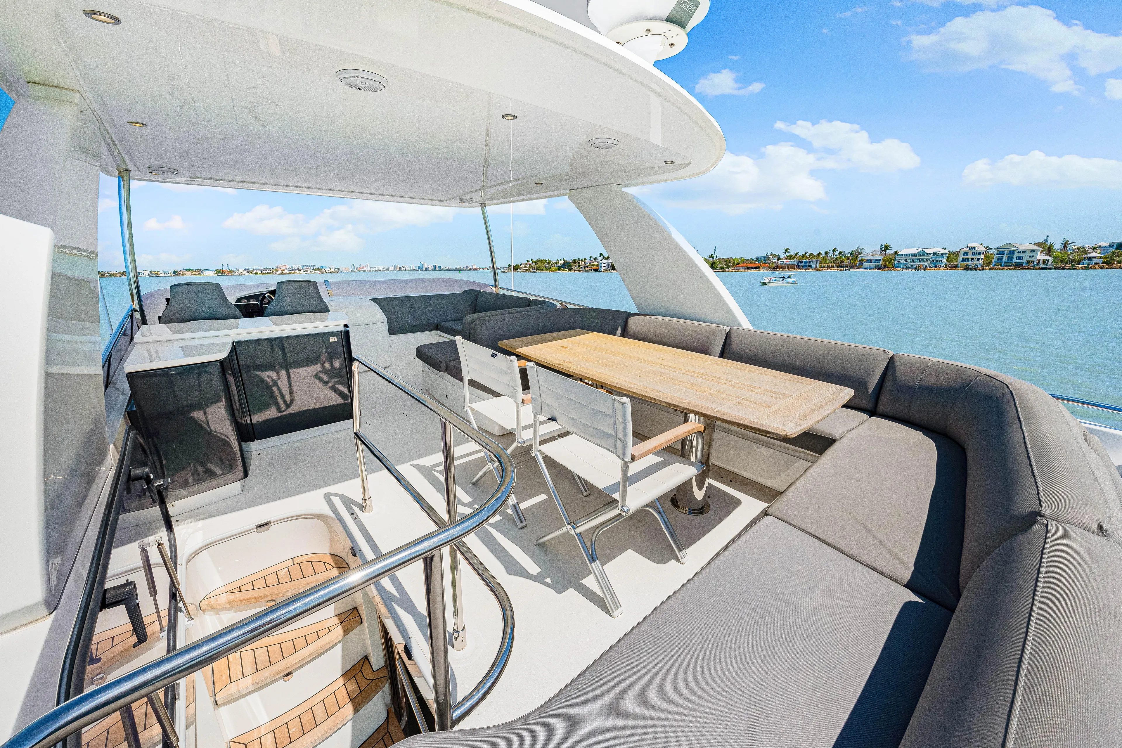 Fuelish Pleasure II Yacht Photos Pics Luxurious 2017 Princess 56 yacht deck with seating and table, overlooking serene waters.