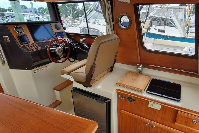 Swell Life Yacht Photos Pics 2021 Ranger Tugs R-25 interior with helm, navigation screens, and compact kitchen area.