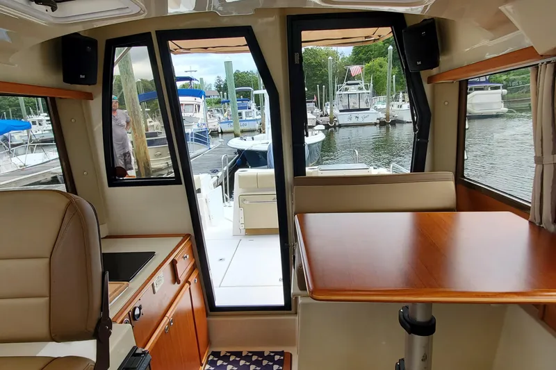 Swell Life Yacht Photos Pics Interior view of 2021 Ranger Tugs R-25 boat, featuring a cozy dining area and marina backdrop.