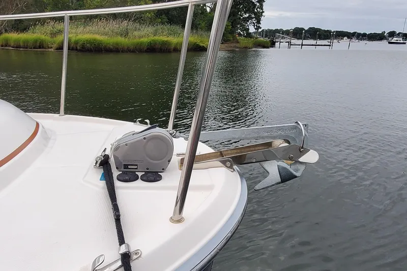 Swell Life Yacht Photos Pics 2021 Ranger Tugs R-25 boat anchor system on calm water, near lush shoreline.