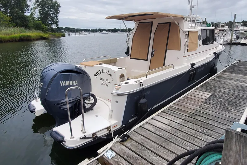 Swell Life Yacht Photos Pics 2021 Ranger Tugs R-25 boat docked, featuring Yamaha outboard motor, in a serene marina setting.