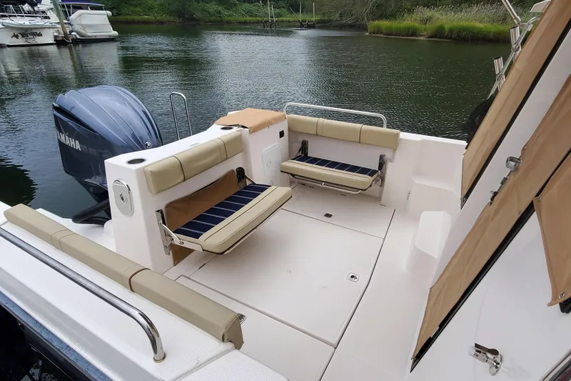 Swell Life Yacht Photos Pics 2021 Ranger Tugs R-25 boat interior with seating, Yamaha engine, and scenic water backdrop.