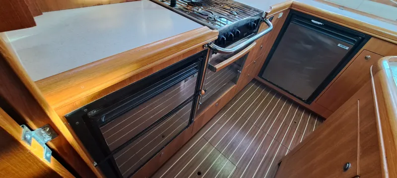Bashful Yacht Photos Pics 2006 Hunter 46 LE yacht kitchen with stove, fridge, and wooden cabinetry.
