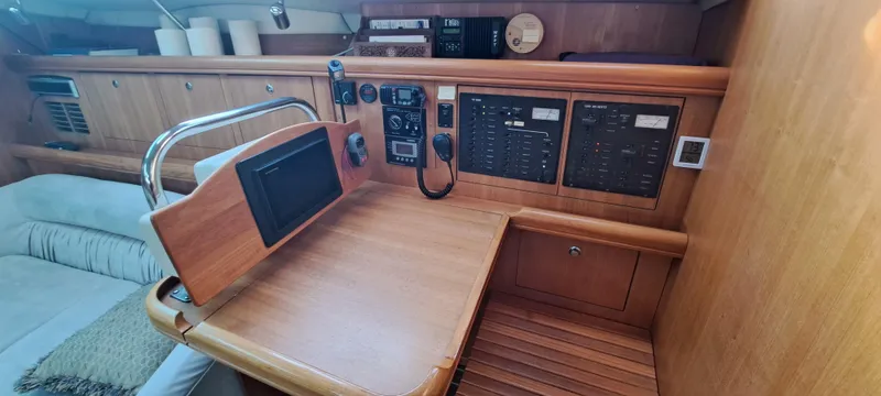 Bashful Yacht Photos Pics Navigation station of a 2006 Hunter 46 LE sailboat with control panels and seating.