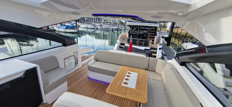 In Stock Yacht Photos Pics 2025 Fairline Targa 45 Open yacht interior with seating and table, docked at marina.
