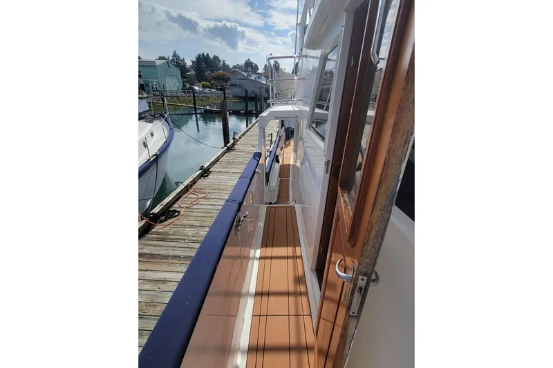 Fellowship Yacht Photos Pics 2001 Grand Alaskan Pilothouse yacht docked, showcasing sleek deck and wooden door.