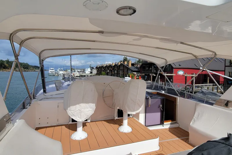 Fellowship Yacht Photos Pics 2001 Grand Alaskan Pilothouse yacht interior with covered seating and scenic marina view.