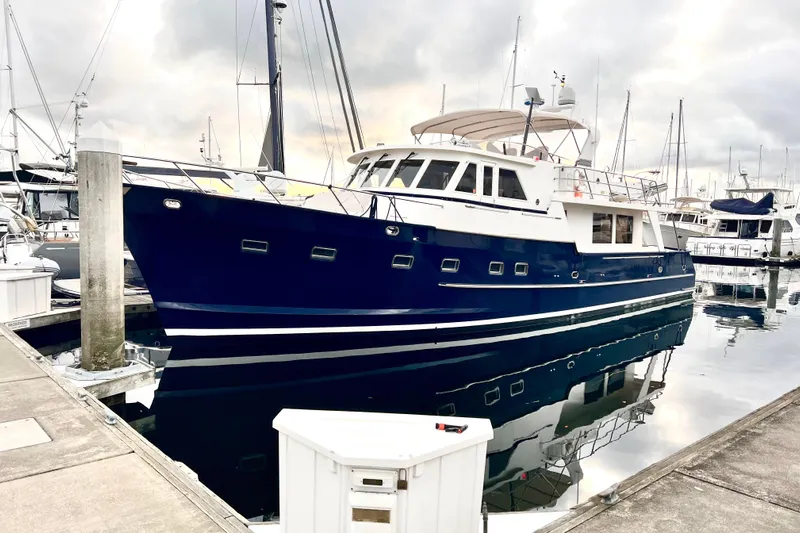 Fellowship Yacht Photos Pics 2001 Grand Alaskan Pilothouse yacht docked at marina, reflecting on calm water.