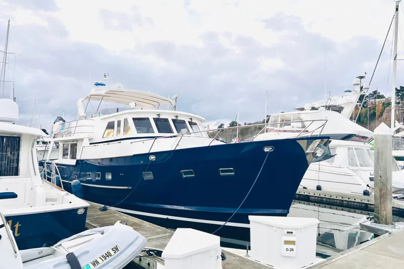 Fellowship Yacht Photos Pics 2001 Grand Alaskan Pilothouse yacht docked at marina under cloudy sky.