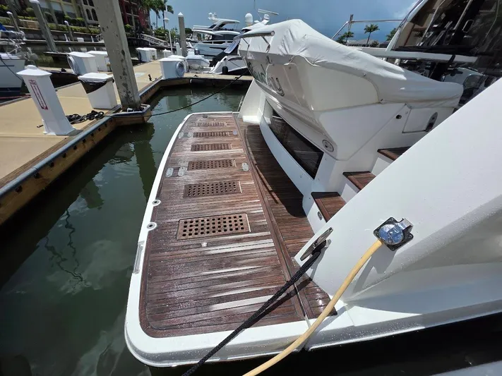 Just Peachy Yacht Photos Pics 2015 Prestige 550 Fly yacht docked, featuring a wooden swim platform and covered seating area.