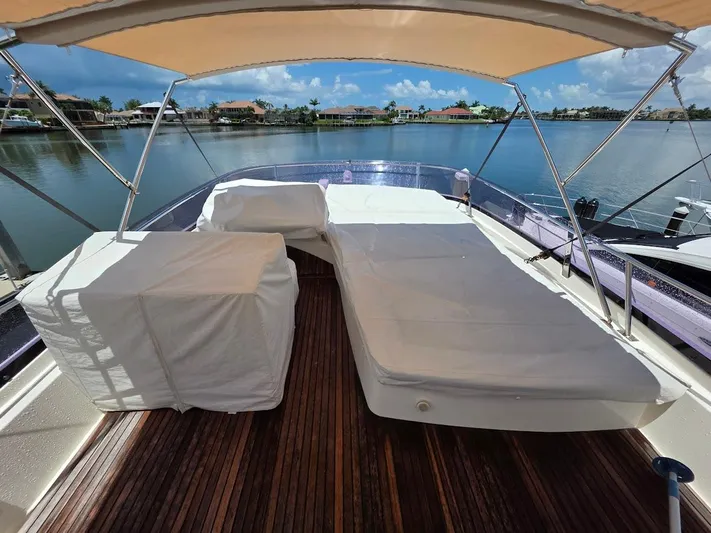 Just Peachy Yacht Photos Pics Luxurious 2015 Prestige 550 Fly yacht deck with sunbed and canopy, overlooking serene waterfront.
