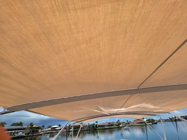Just Peachy Yacht Photos Pics Canvas canopy on a 2015 Prestige 550 Fly yacht, overlooking a serene waterfront view.