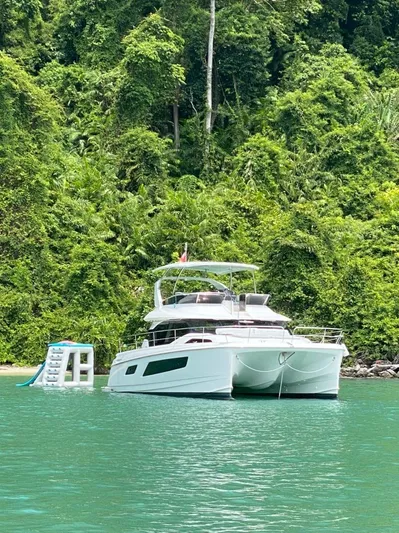 Charis Yacht Photos Pics Aquila 44 Yacht 2020 anchored near lush green forest, with inflatable slide.