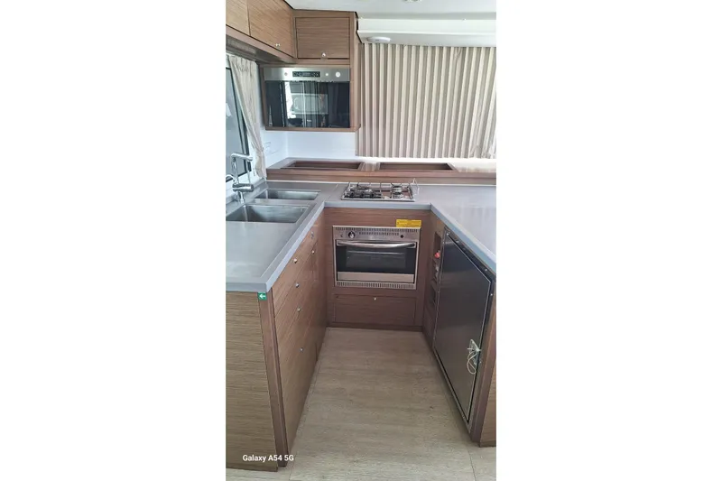  Yacht Photos Pics Modern kitchen interior of 2018 Lagoon 450 F catamaran with wood cabinetry and stainless steel appliances.