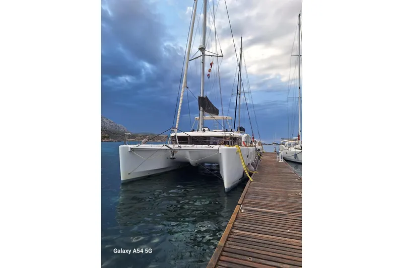  Yacht Photos Pics 2018 Lagoon 450 F catamaran docked at a wooden pier under a cloudy sky.