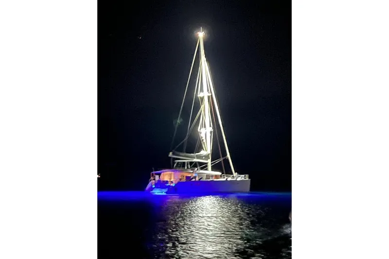  Yacht Photos Pics Illuminated Lagoon 450 F catamaran at night, 2018 model, with glowing blue water reflection.