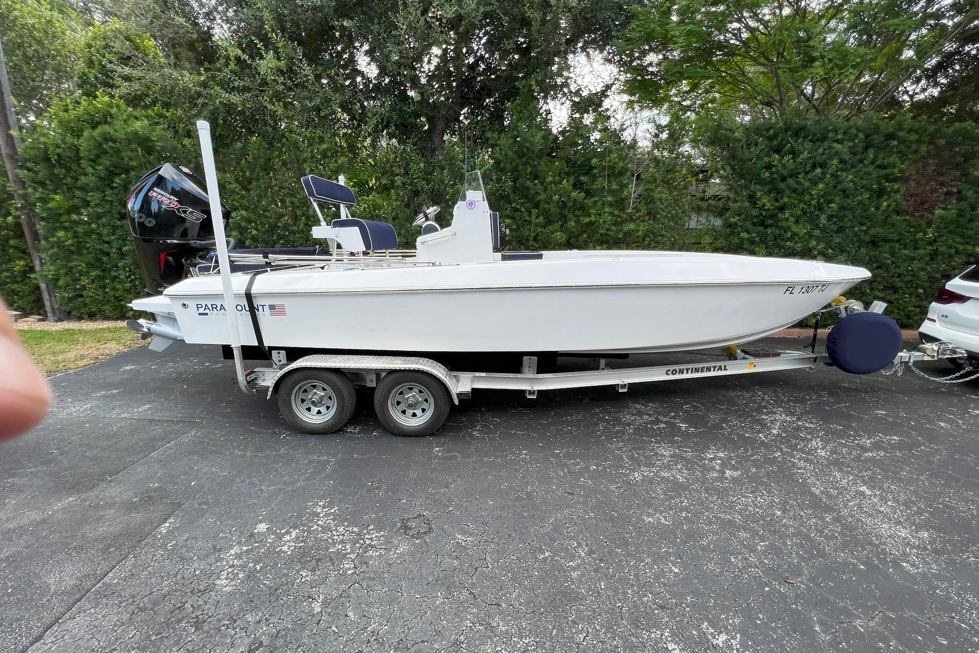 2022 Paramount 21 boat on trailer, parked outdoors with lush greenery background.