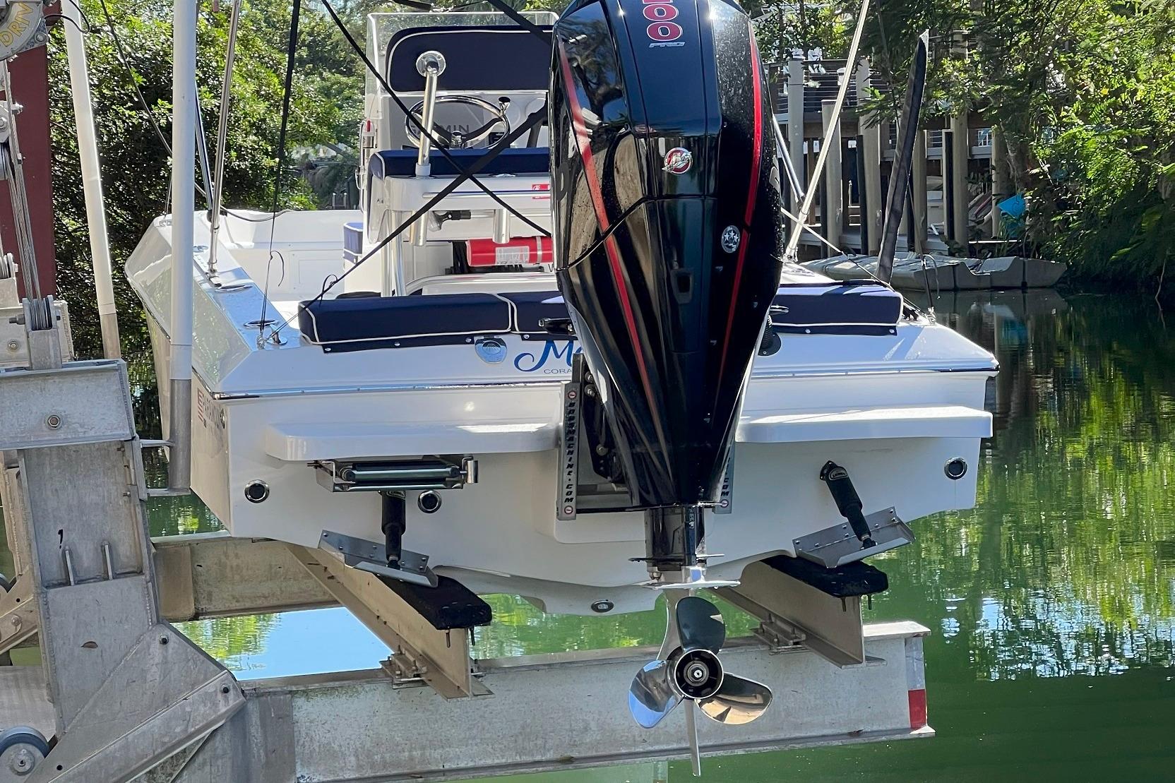 2022 Paramount 21 boat with powerful outboard motor on a lift by the water.