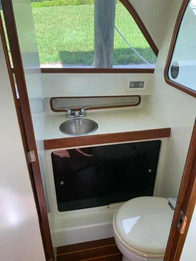 Legacy Yacht Photos Pics 1973 Bertram 31 Flybridge Cruiser bathroom with sink and toilet, featuring wood accents.