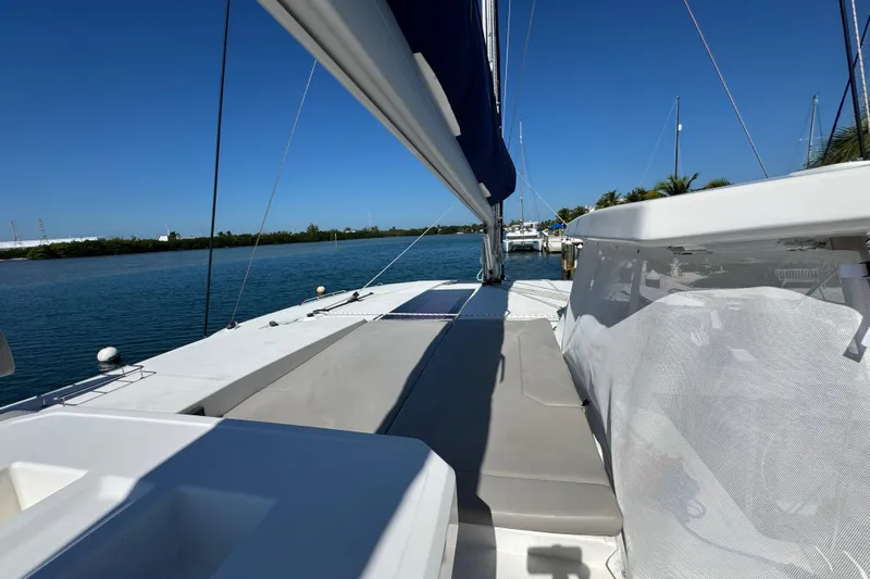 Ce Ya Yacht Photos Pics 2021 Leopard 45 catamaran deck with sunbathing area, docked by calm waters.
