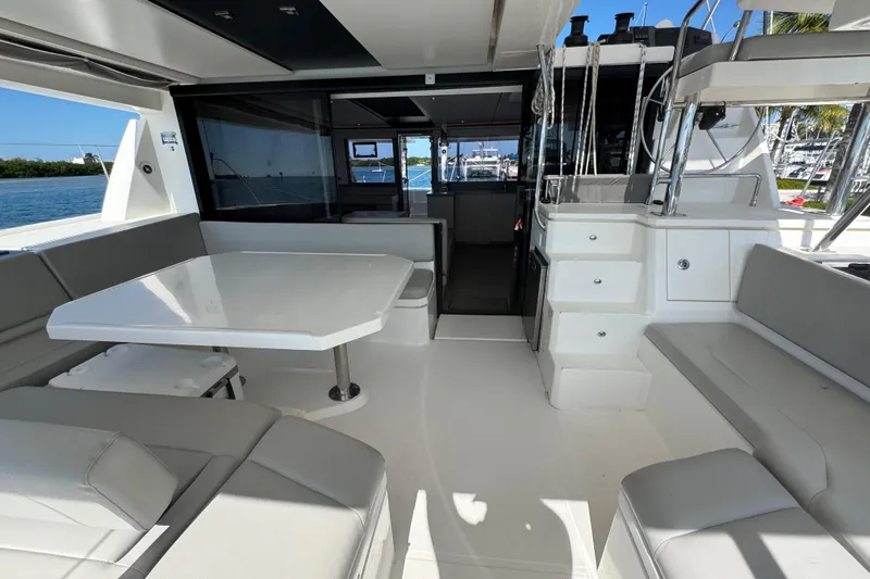 Ce Ya Yacht Photos Pics Spacious interior of 2021 Leopard 45 catamaran with seating and table, docked by the water.
