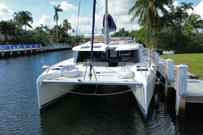 Ce Ya Yacht Photos Pics 2021 Leopard 45 catamaran docked by palm trees, under a clear blue sky.