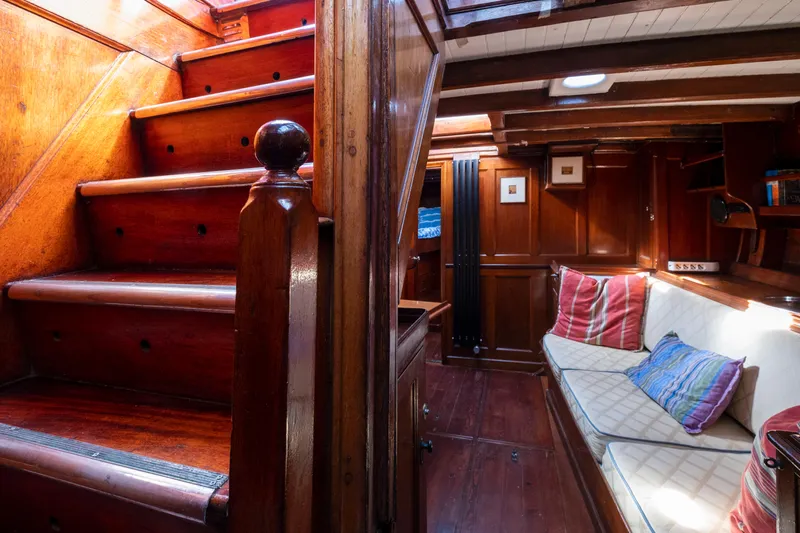Juliette Yacht Photos Pics Interior of 1929 Custom Cutter Marconi yacht with wooden stairs and cozy seating area.