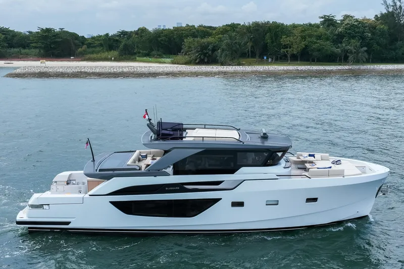  Yacht Photos Pics 2023 Bluegame BGX60 yacht cruising near a lush, green shoreline.